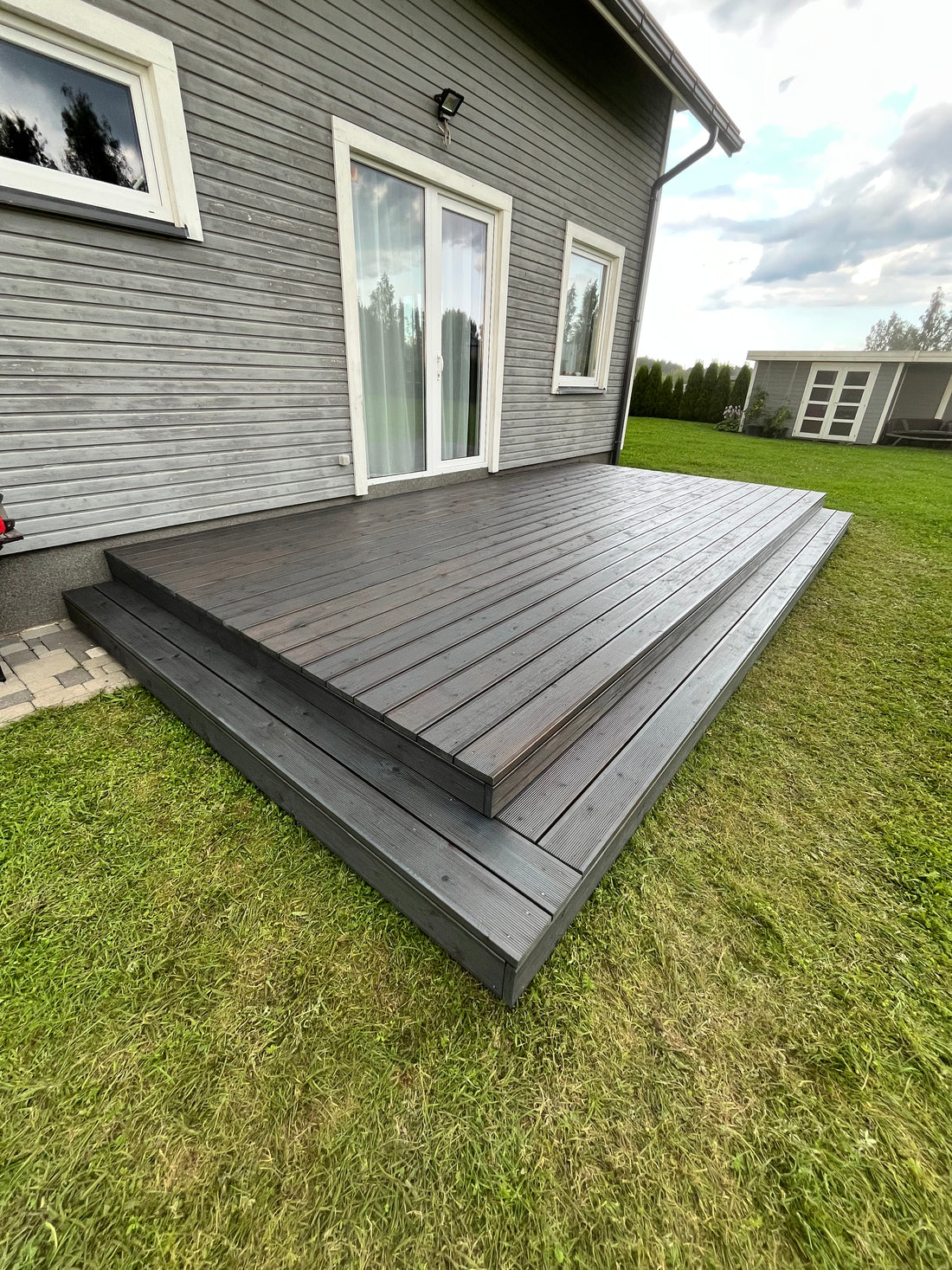 Wooden deck extension on a house with grass and sky in the background