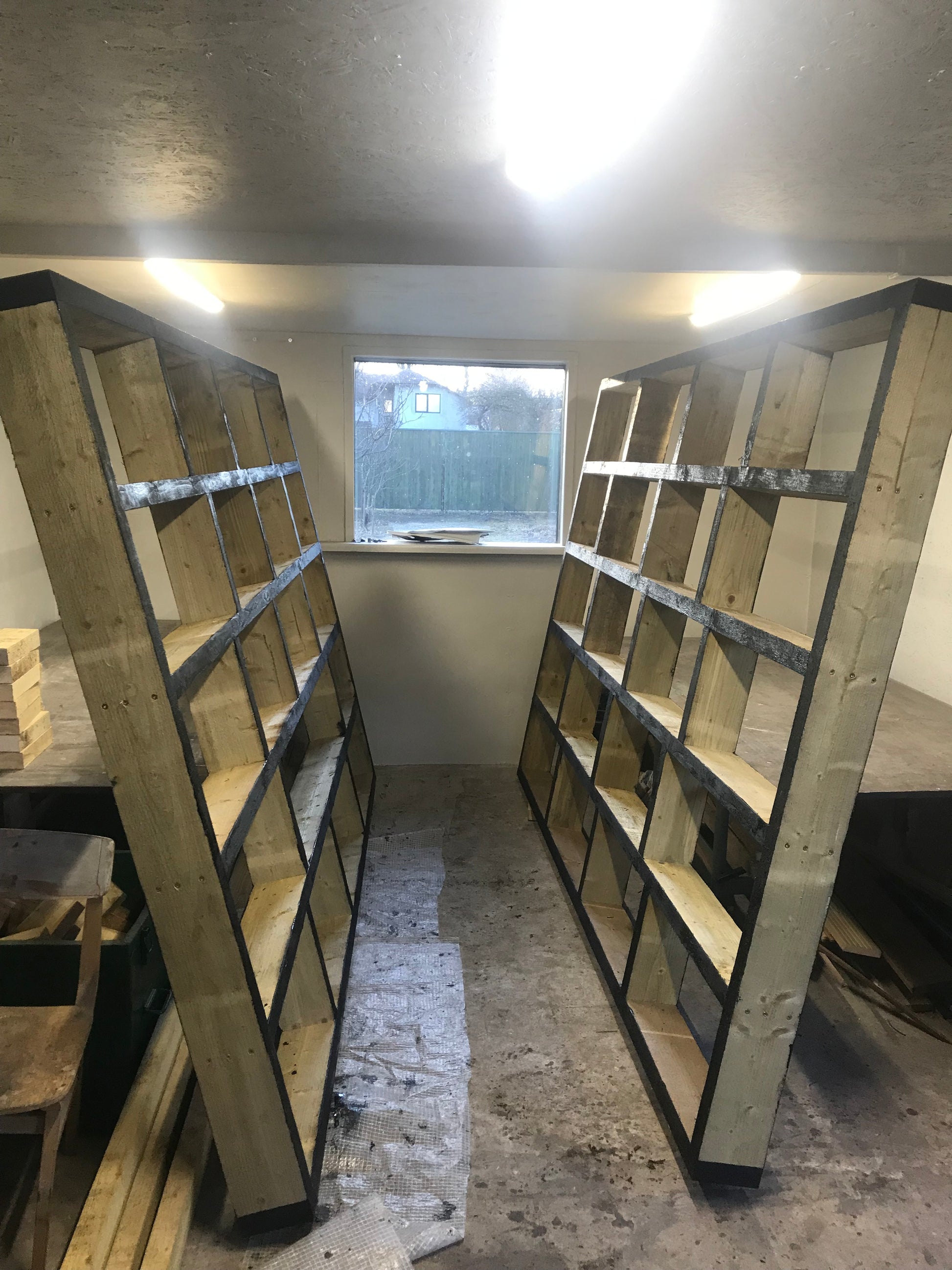 Wooden shelves against a concrete wall with a window in the background