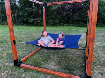 Two children playing on a blue hammock or relaxation cube made by modular solutions