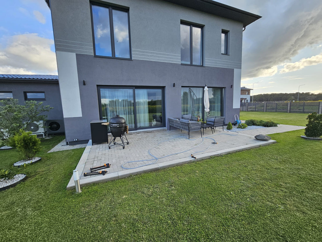 Modern house exterior with patio furniture and a well-maintained lawn.