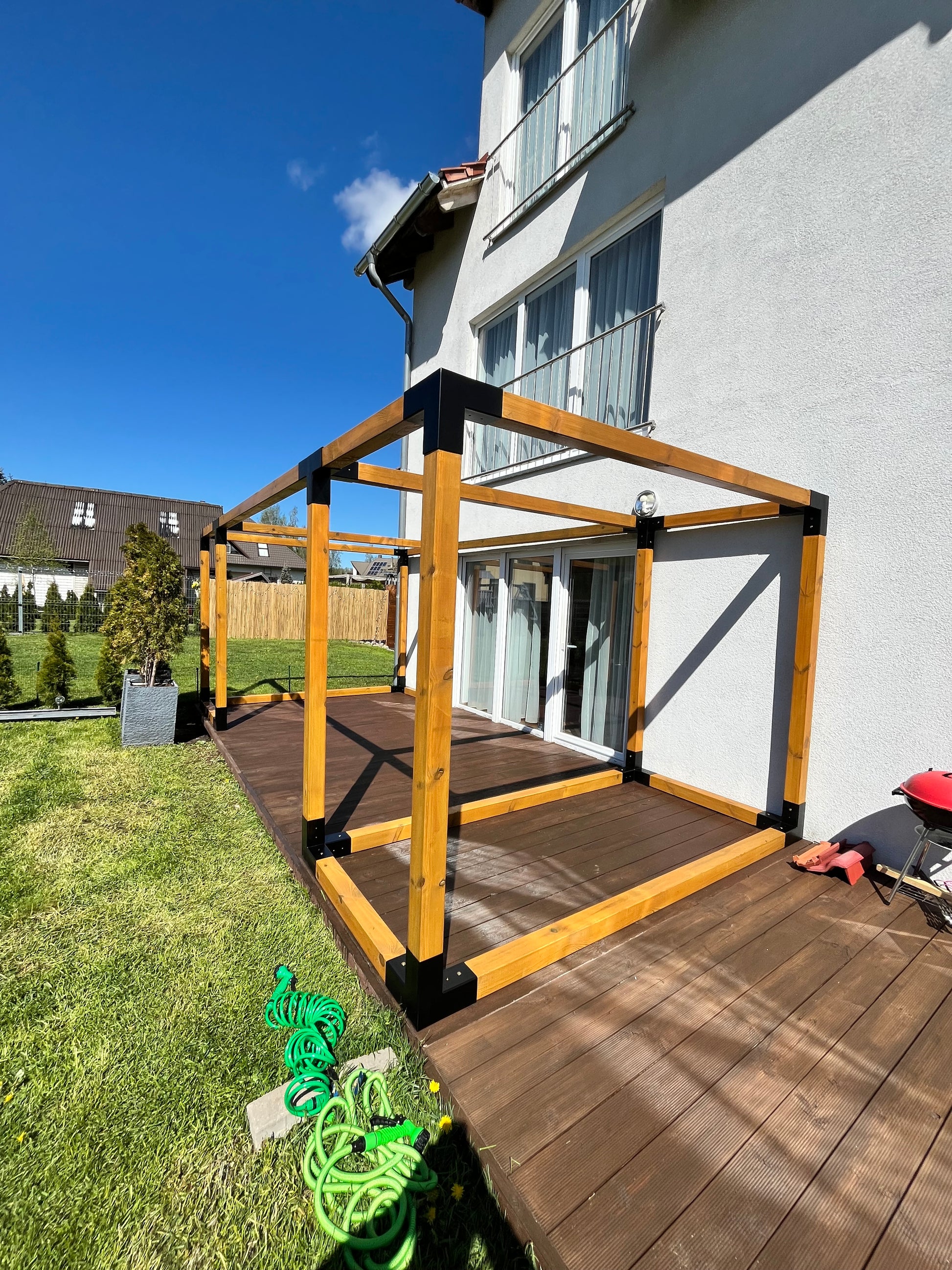 Yellow metal pergola frame on a patio with buildings and blue sky in the background