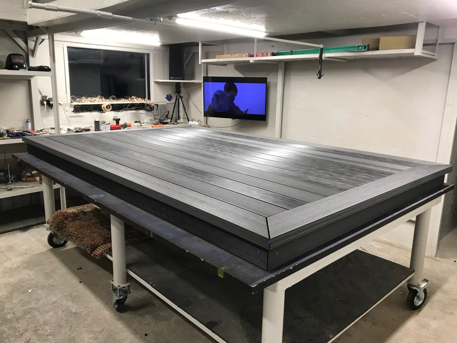 Large flat worktable in a workshop setting with tools and equipment around.