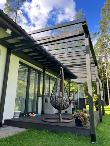Outdoor patio area with a pergola, table, and chairs on a grassy lawn.