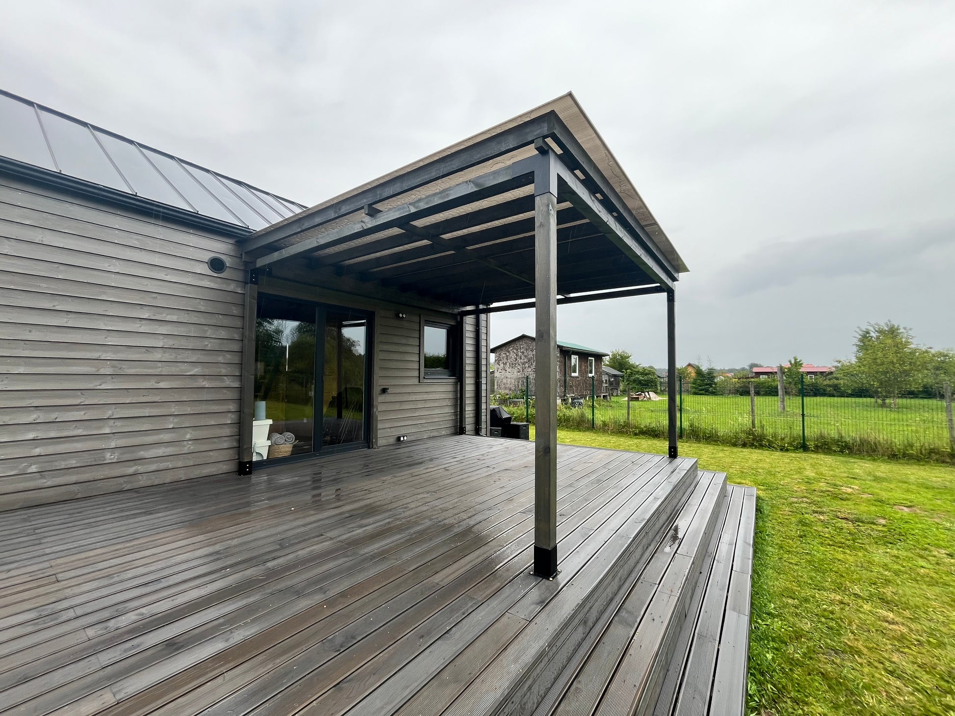 Wooden deck area of a modern house with a view of a rural landscape.