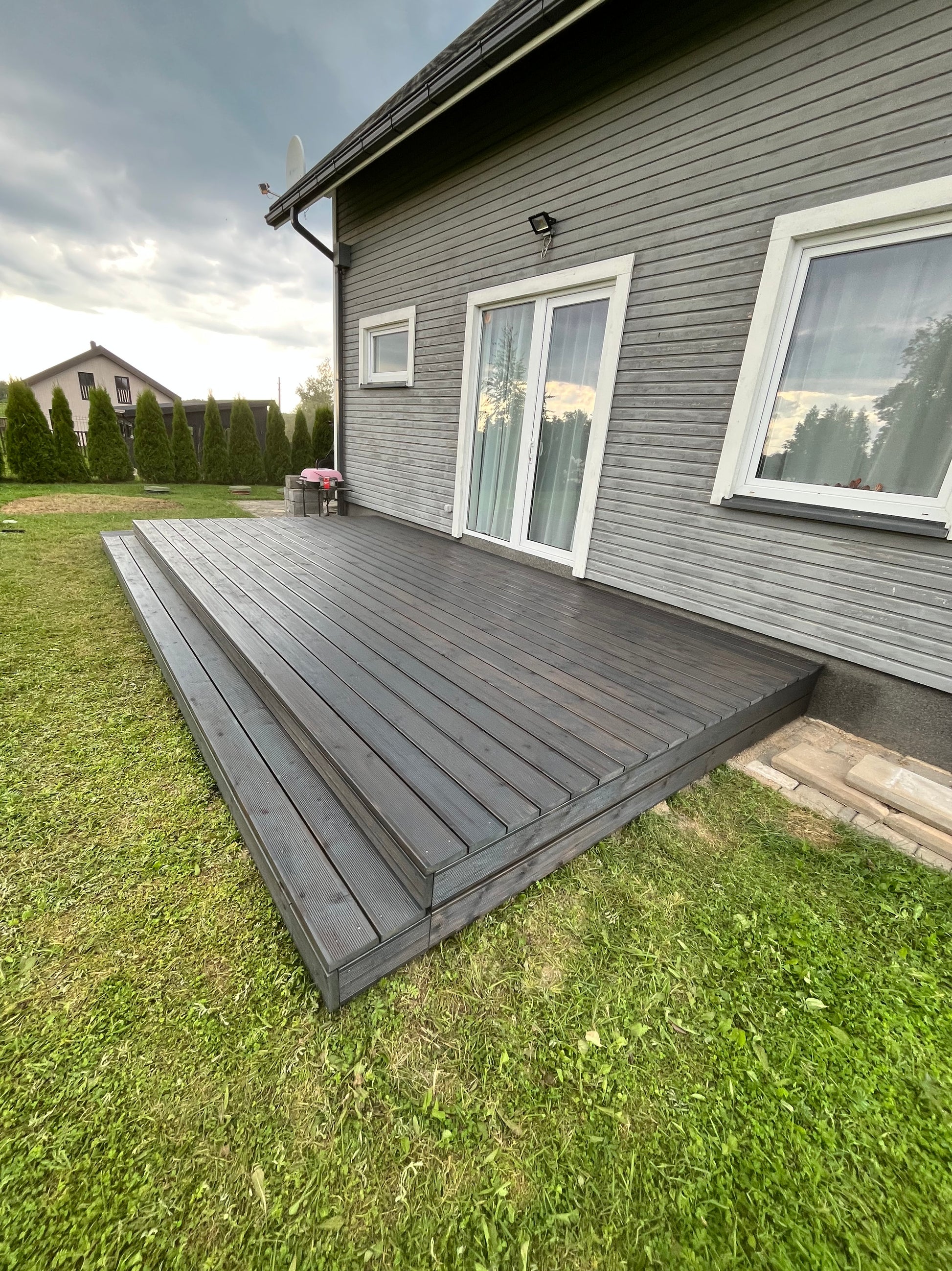 Gray house exterior with a deck and grassy area