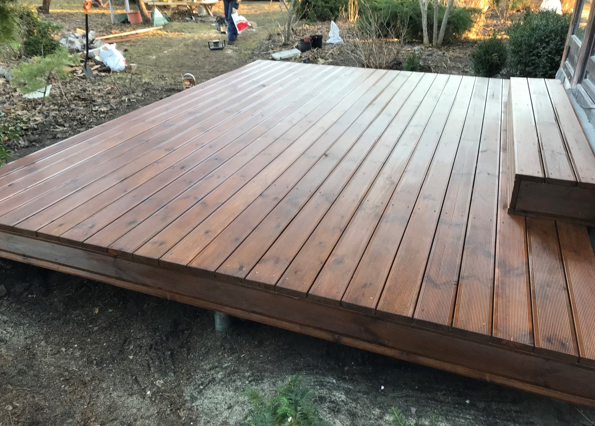 Wooden deck with a grassy area and tools in the background