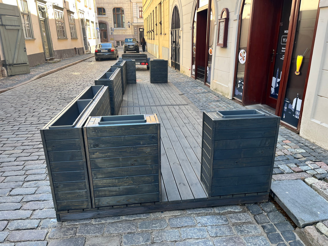 Wooden bench against a stone wall on a street with buildings in the background
