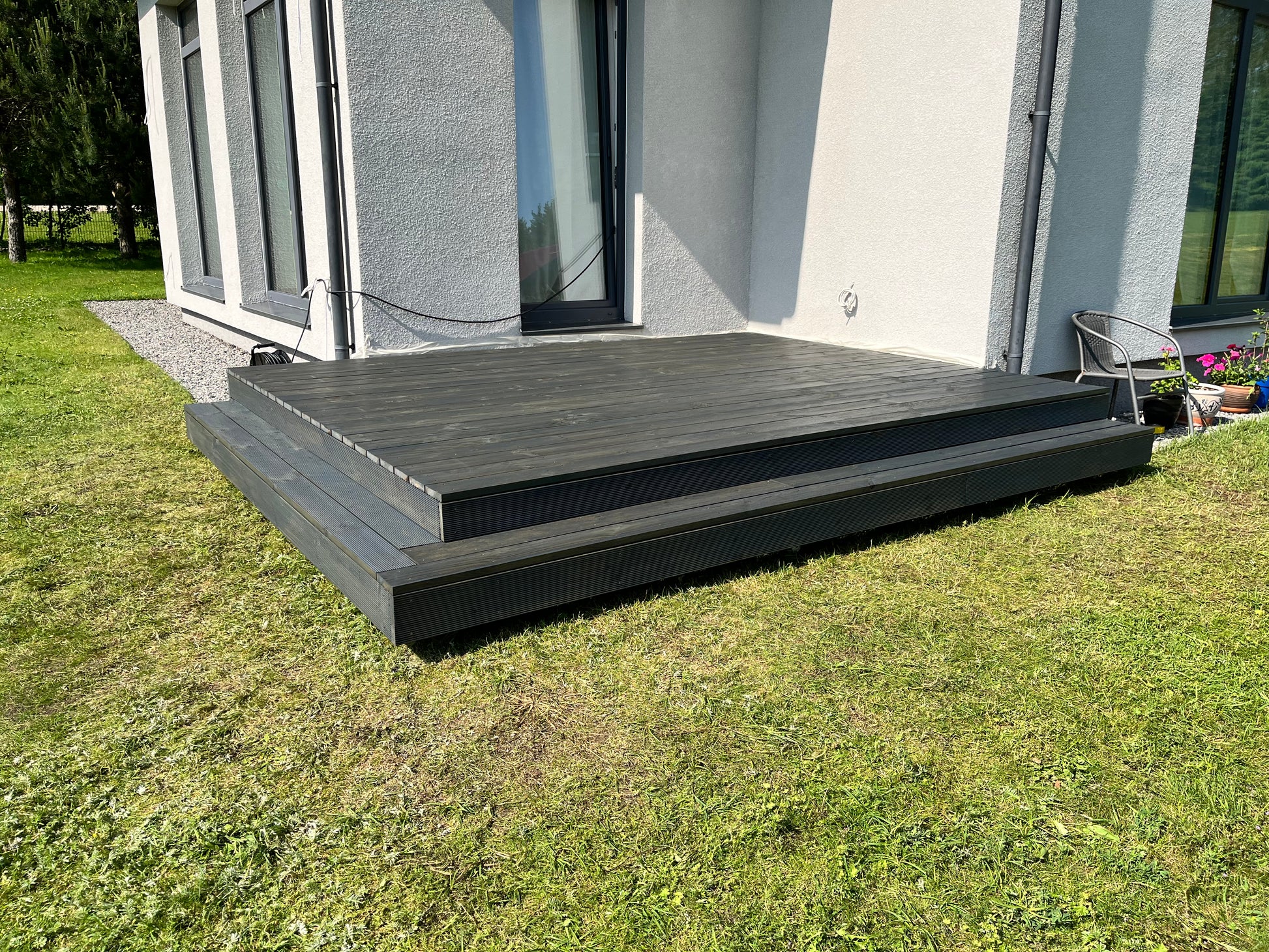 Modern house exterior with a gray deck and steps leading up to it.