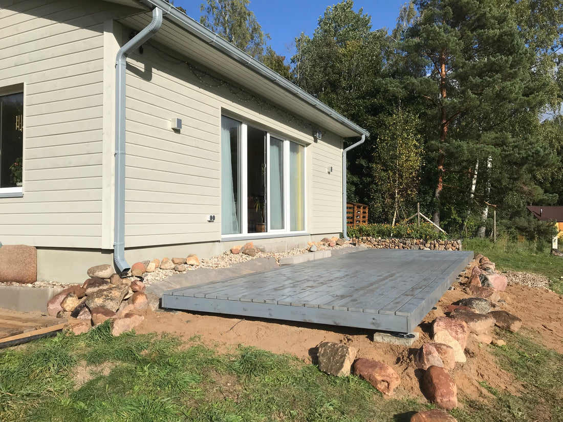 Modern house exterior with a stone patio and surrounding trees